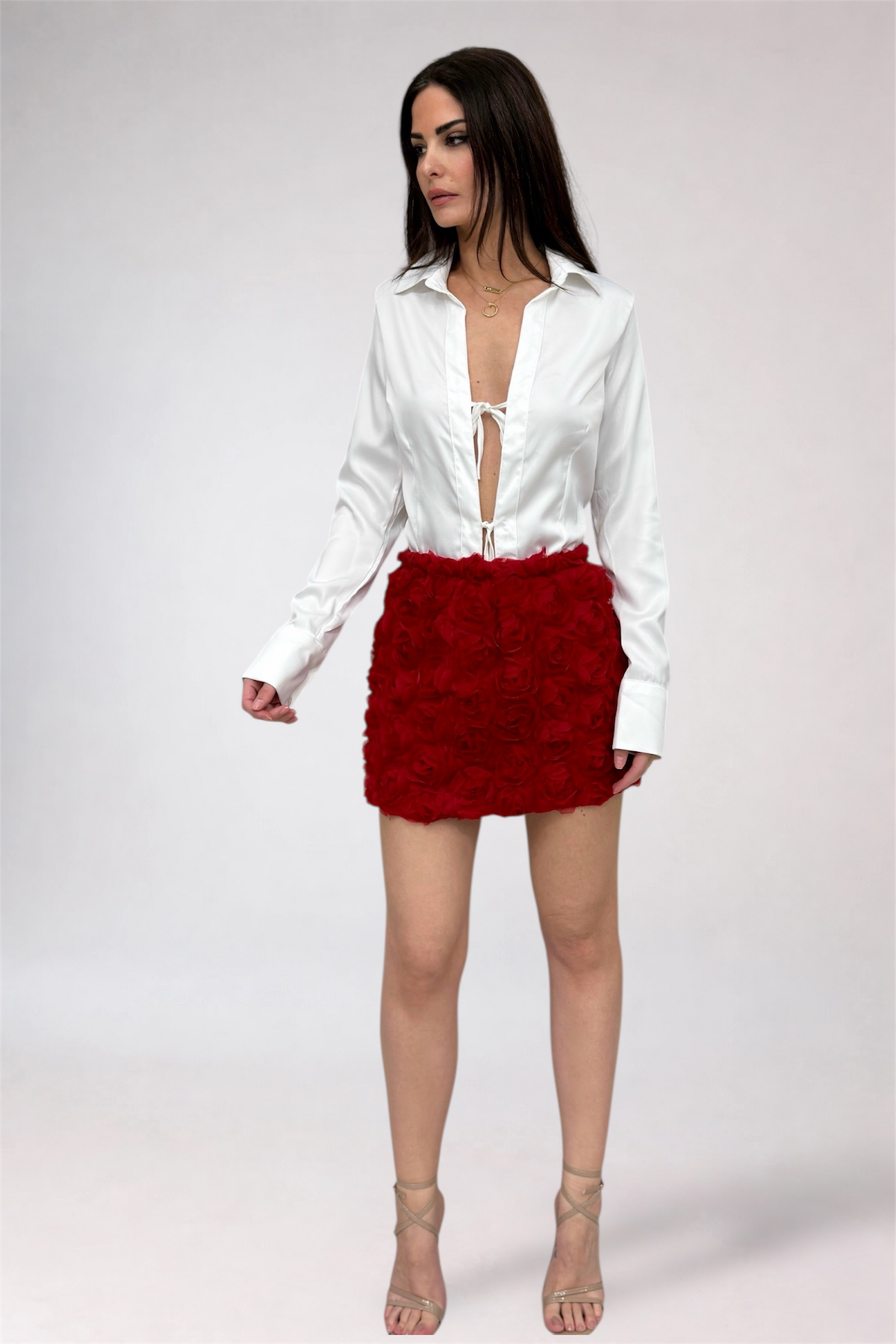 Woman wearing a white blouse and red skirt on a plain background