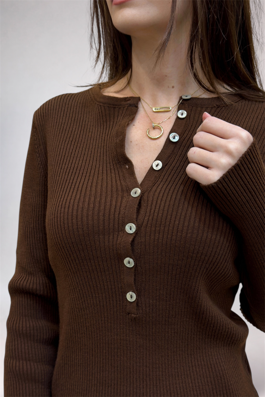 Brown ribbed sweater with buttons worn by a person on a plain background