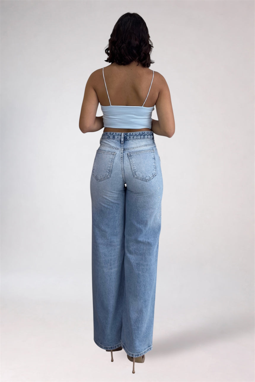Person wearing light blue jeans and a matching top on a white background