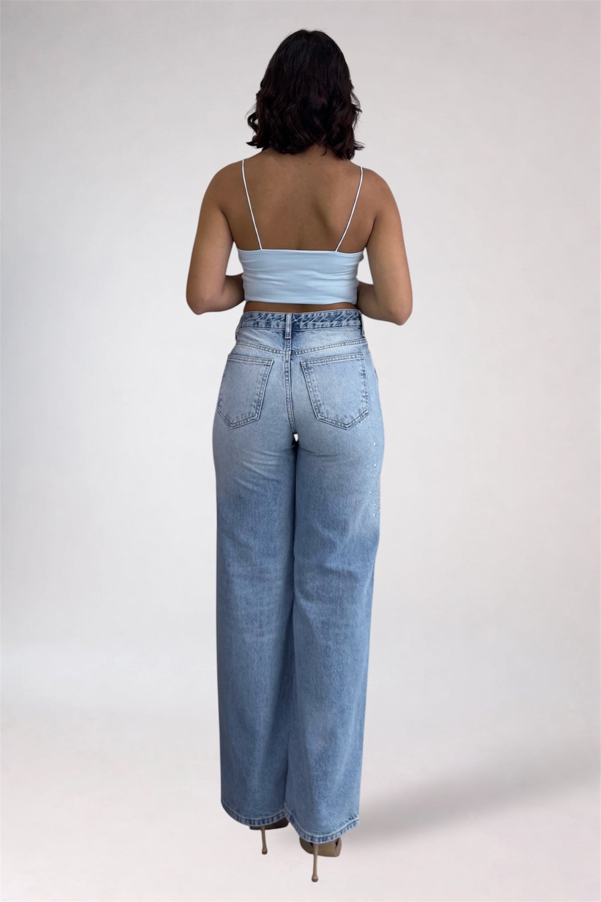 Person wearing light blue jeans and a matching top on a white background