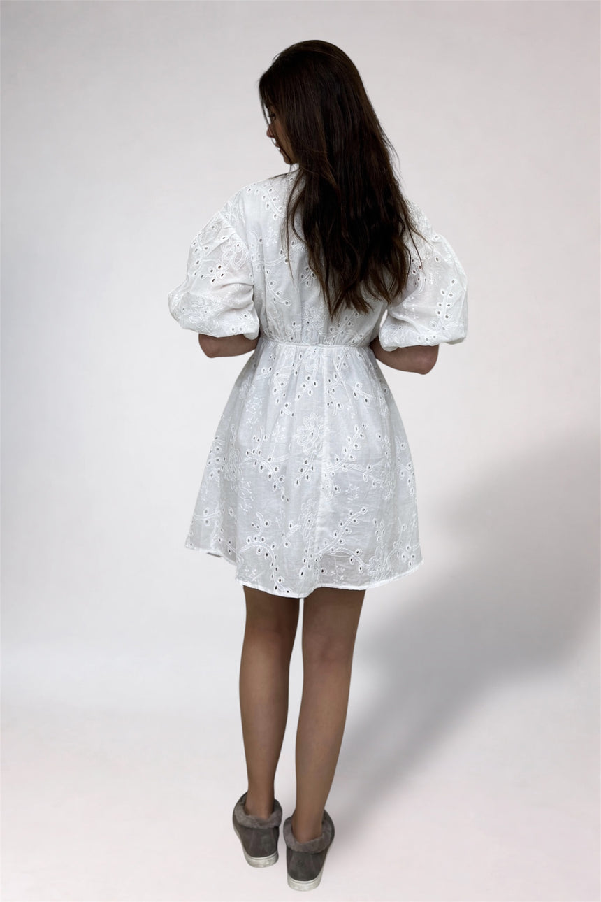 Woman wearing a white lace dress against a plain background