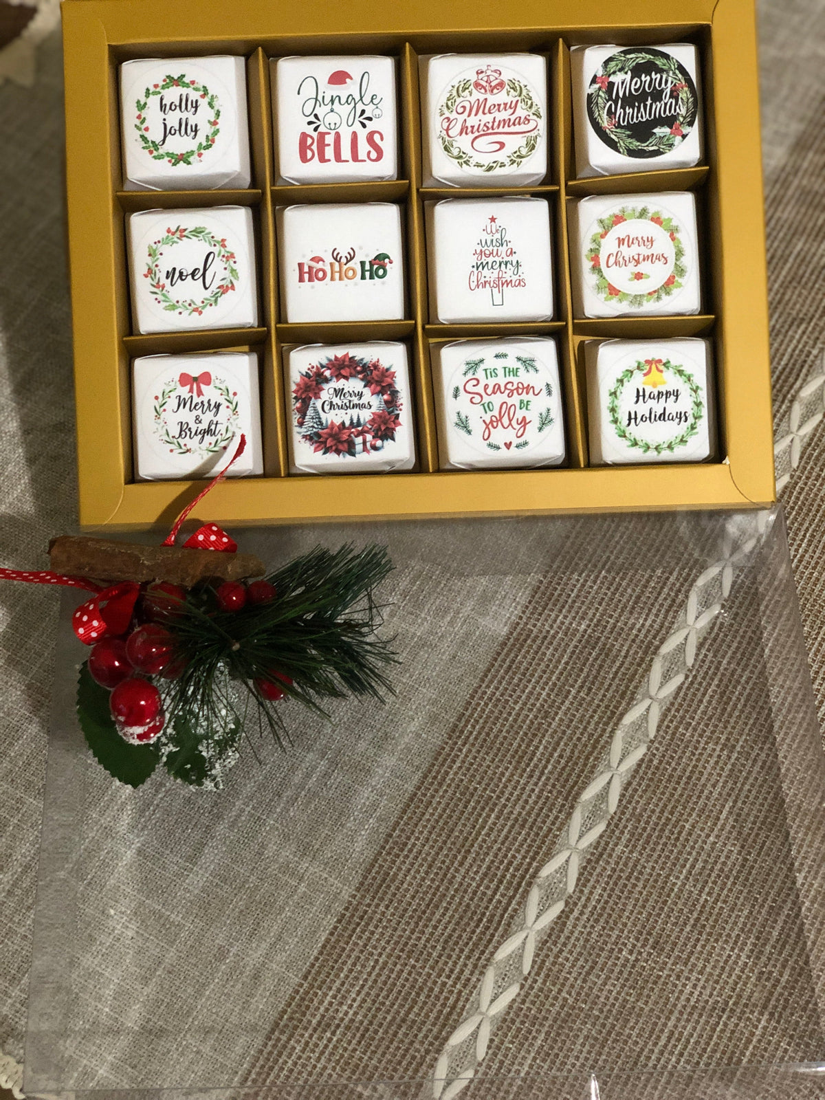 Set of Twelve Christmas-themed coasters in a decorative box on a textured surface.