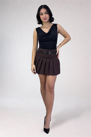 Woman wearing a black top and brown pleated skirt on a white background