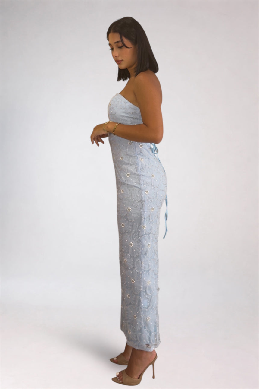 Woman wearing a light blue strapless dress with a pattern on a white background