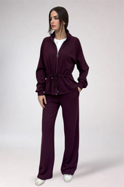 Woman wearing a burgundy tracksuit on a white background