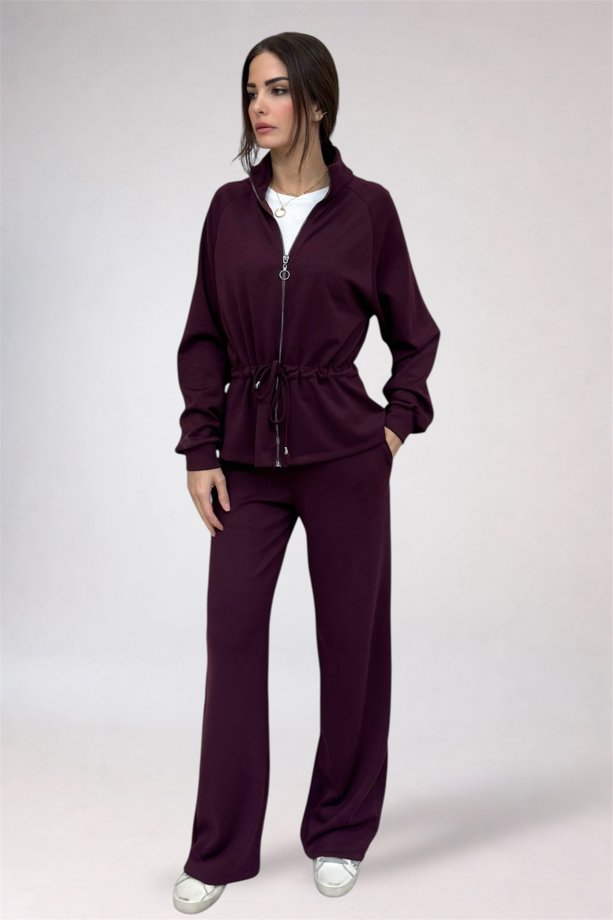 Woman wearing a burgundy tracksuit on a white background