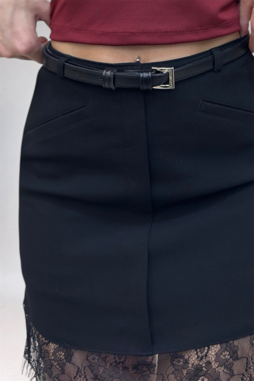 Black skirt worn by a person with a red top, on a plain background