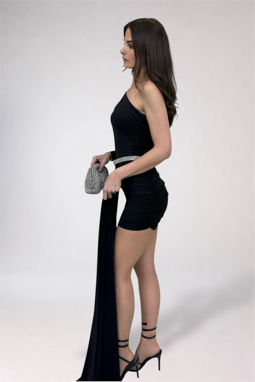 Woman in a black dress holding a long black fabric against a white background