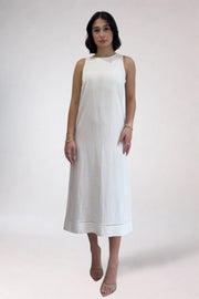 Woman wearing a white sleeveless dress on a plain background