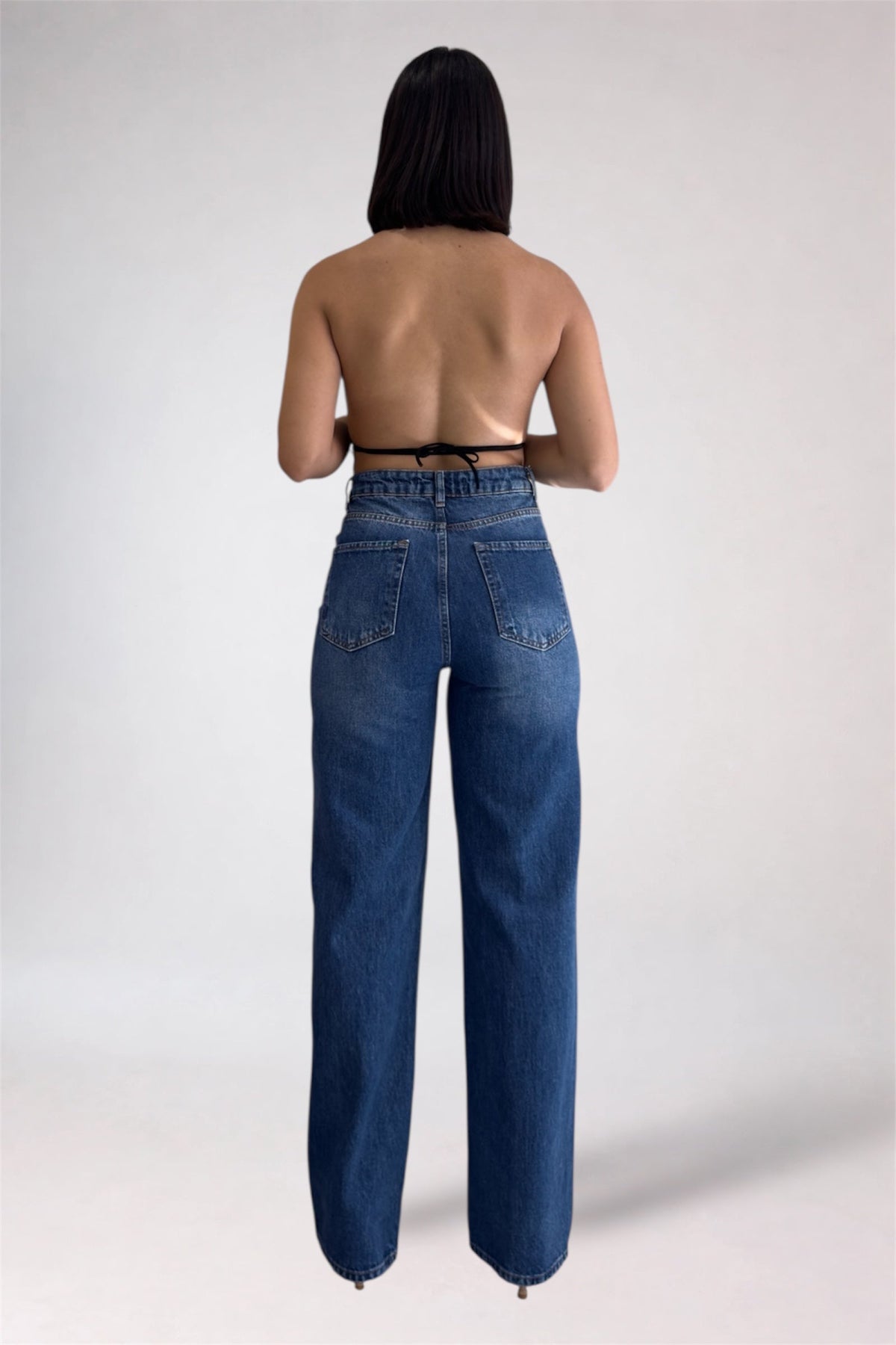 Person wearing blue jeans on a plain background