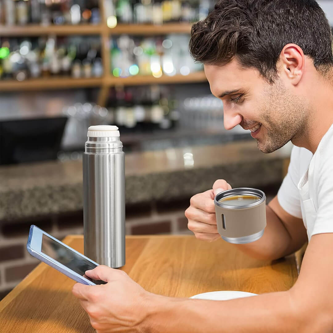 Man sitting with a thermos and coffee cup on the table.