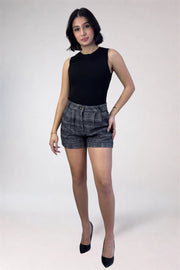 Woman wearing a black sleeveless top and patterned shorts on a white background