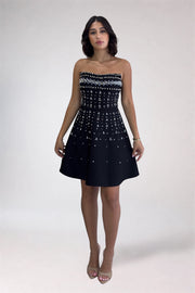 Woman wearing a strapless black dress with white pattern on a white background