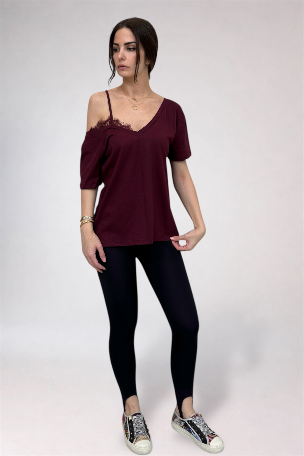 Woman wearing a burgundy top and black leggings on a white background