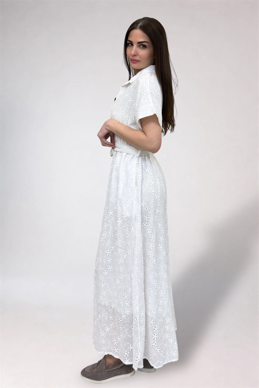 Woman wearing a white dress with a subtle pattern on a plain background
