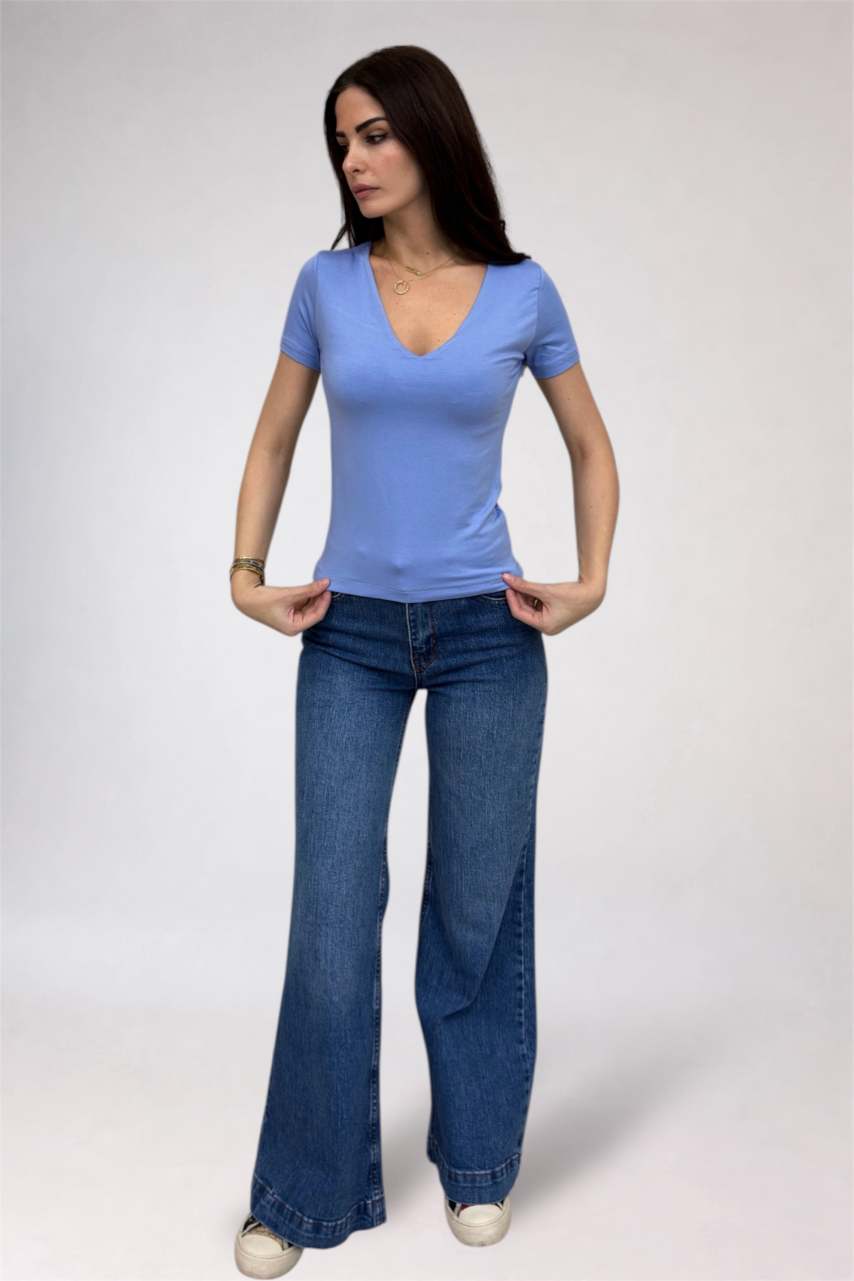 Woman wearing a blue t-shirt and jeans on a plain background