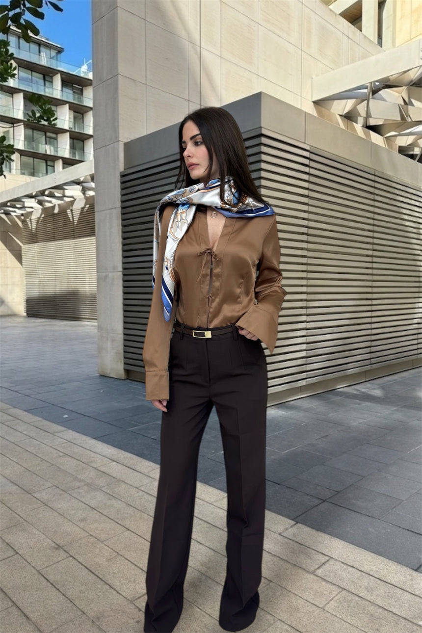 Woman in a brown outfit with a scarf standing in an urban setting