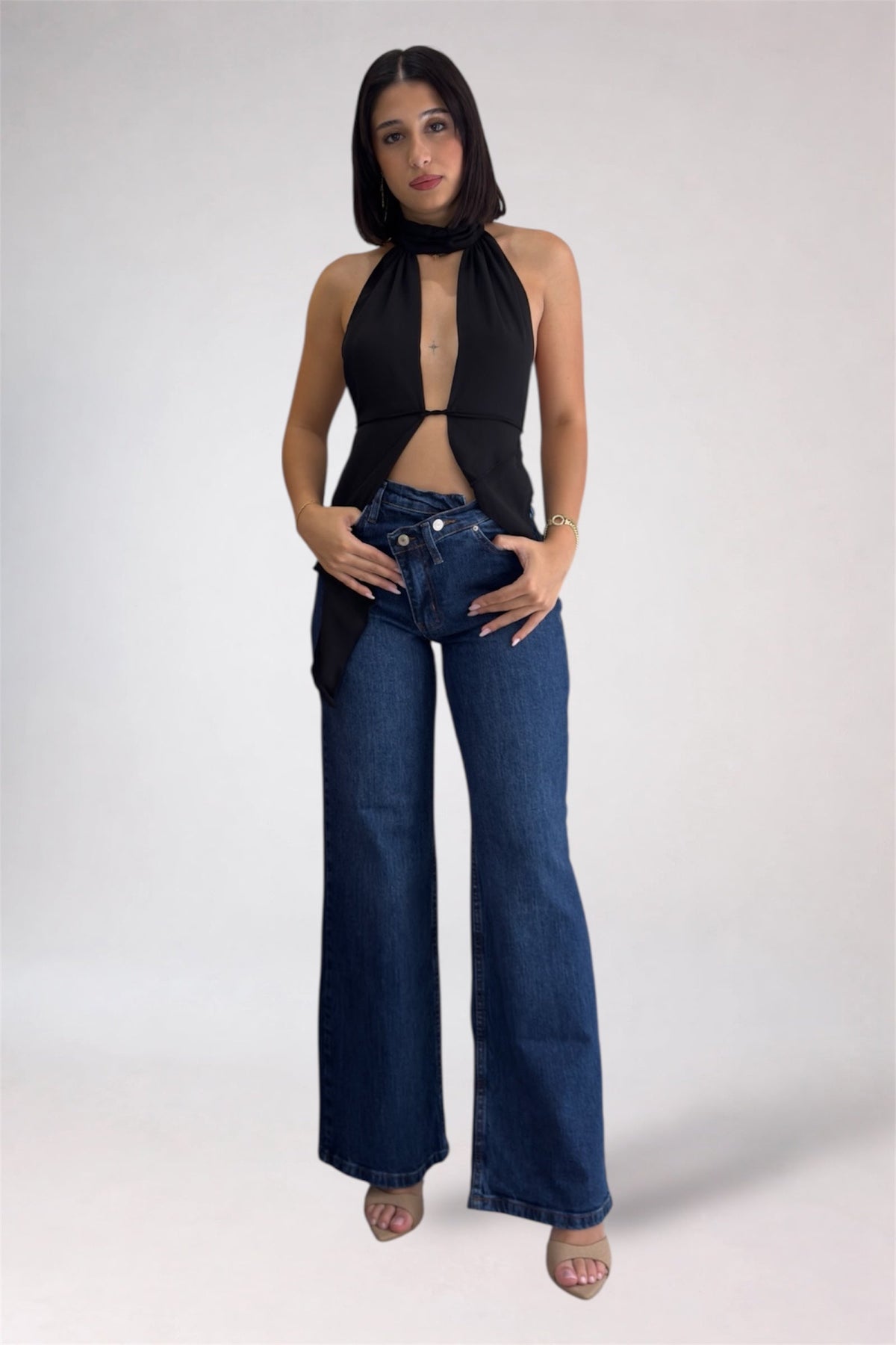 Woman wearing a black halter top and blue jeans on a white background