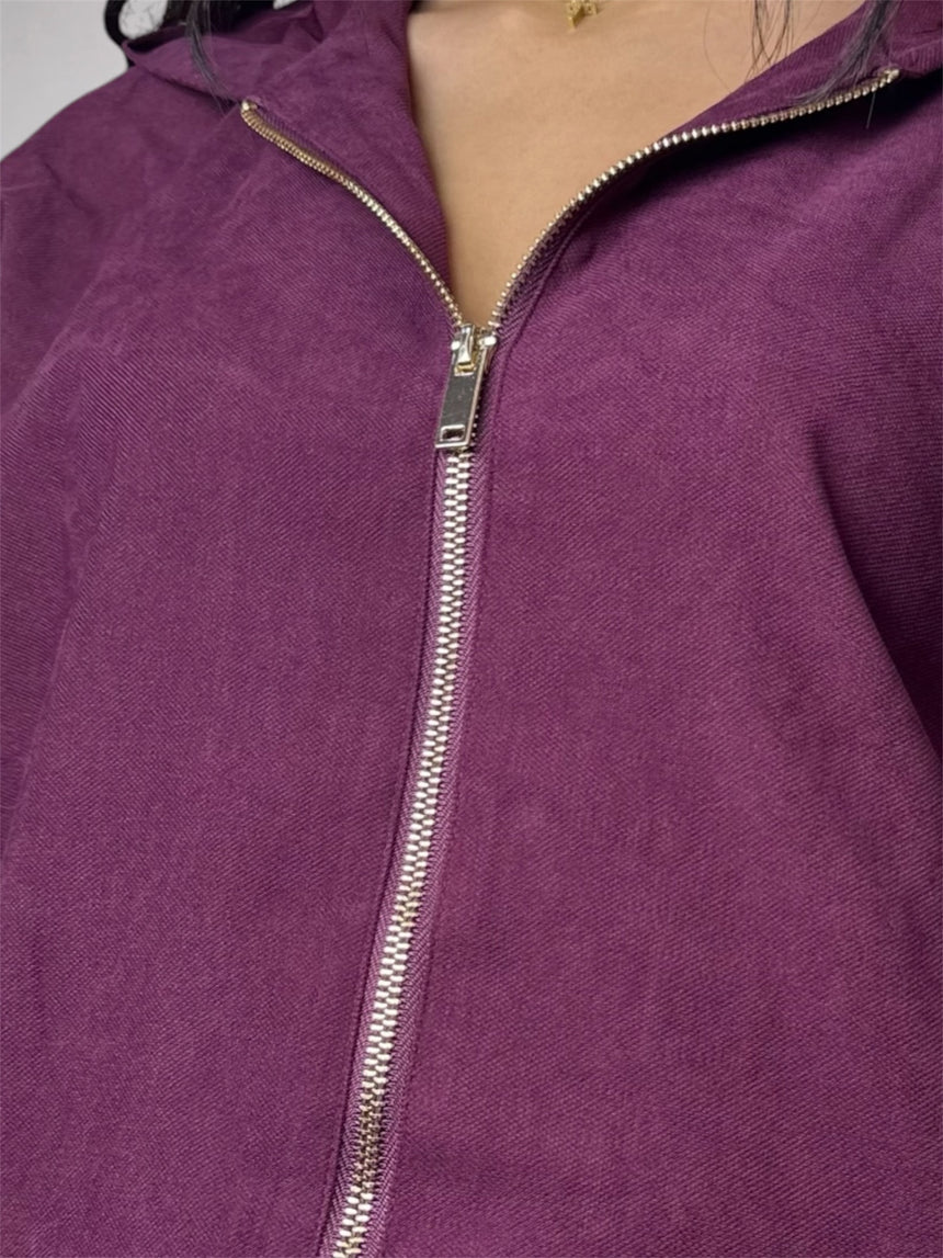 Close-up of a purple zip-up hoodie with a silver metal zipper, worn by a model.