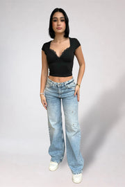 Woman wearing a black top and blue jeans on a plain background