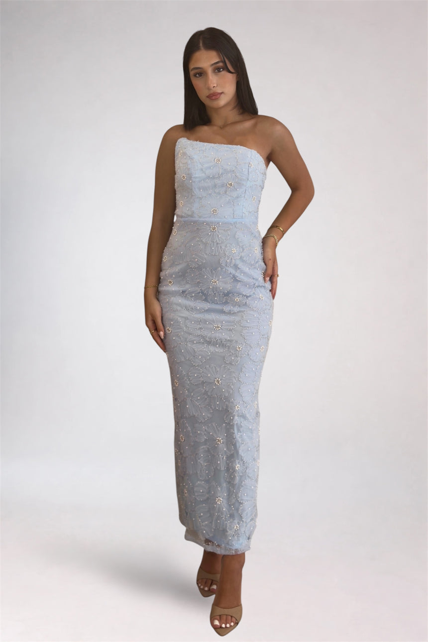 Woman wearing a strapless, light blue dress with a subtle pattern on a white background