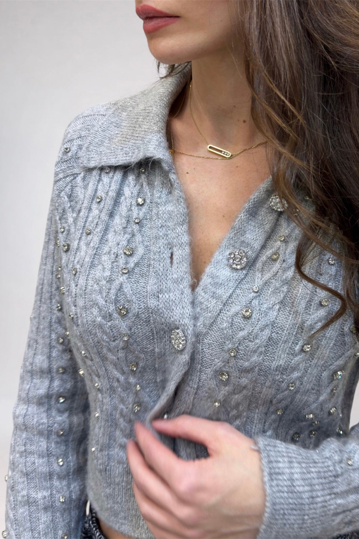 Close-up of a person wearing a gray textured coat with decorative buttons on a plain background