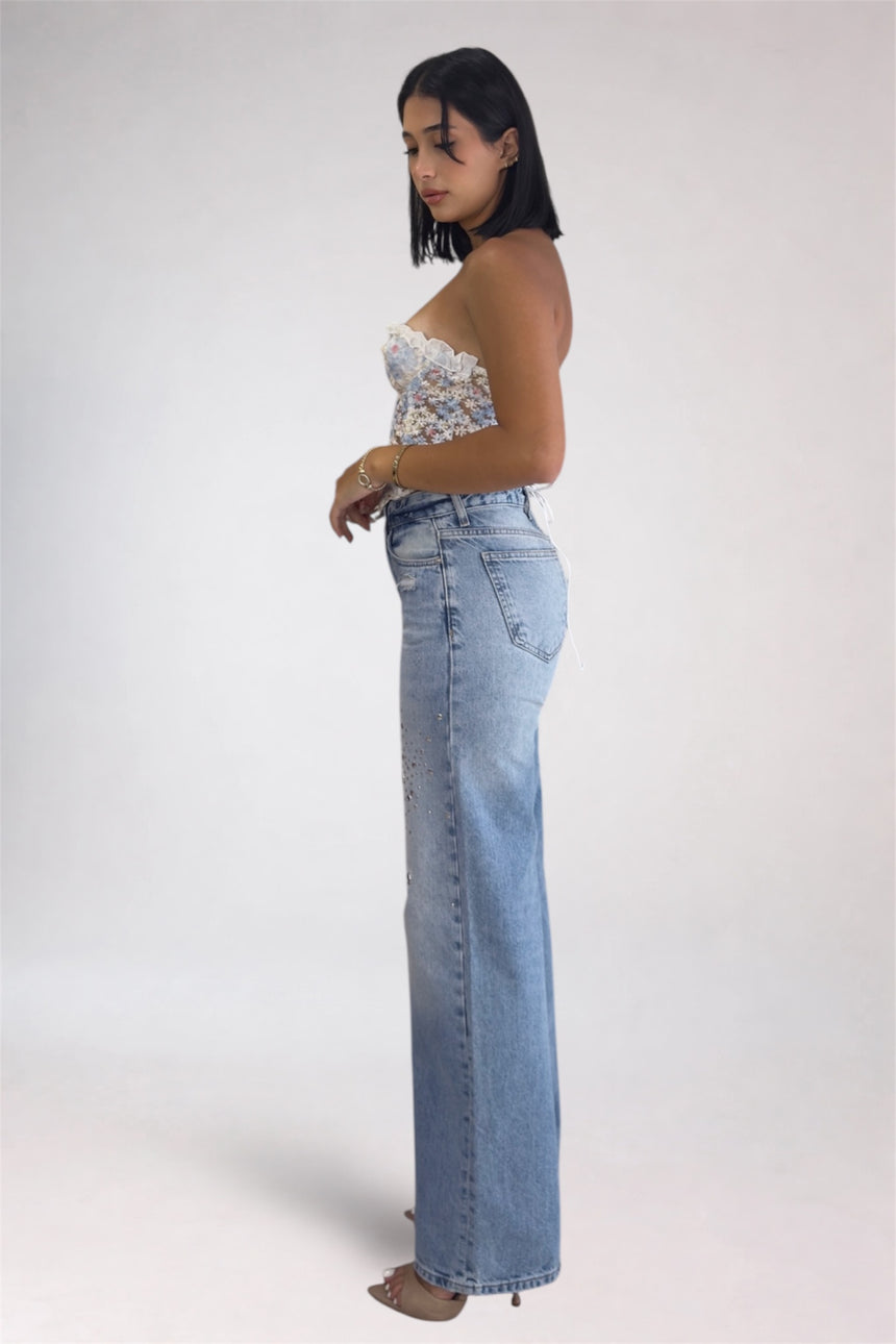 Woman wearing a floral top and blue jeans on a white background