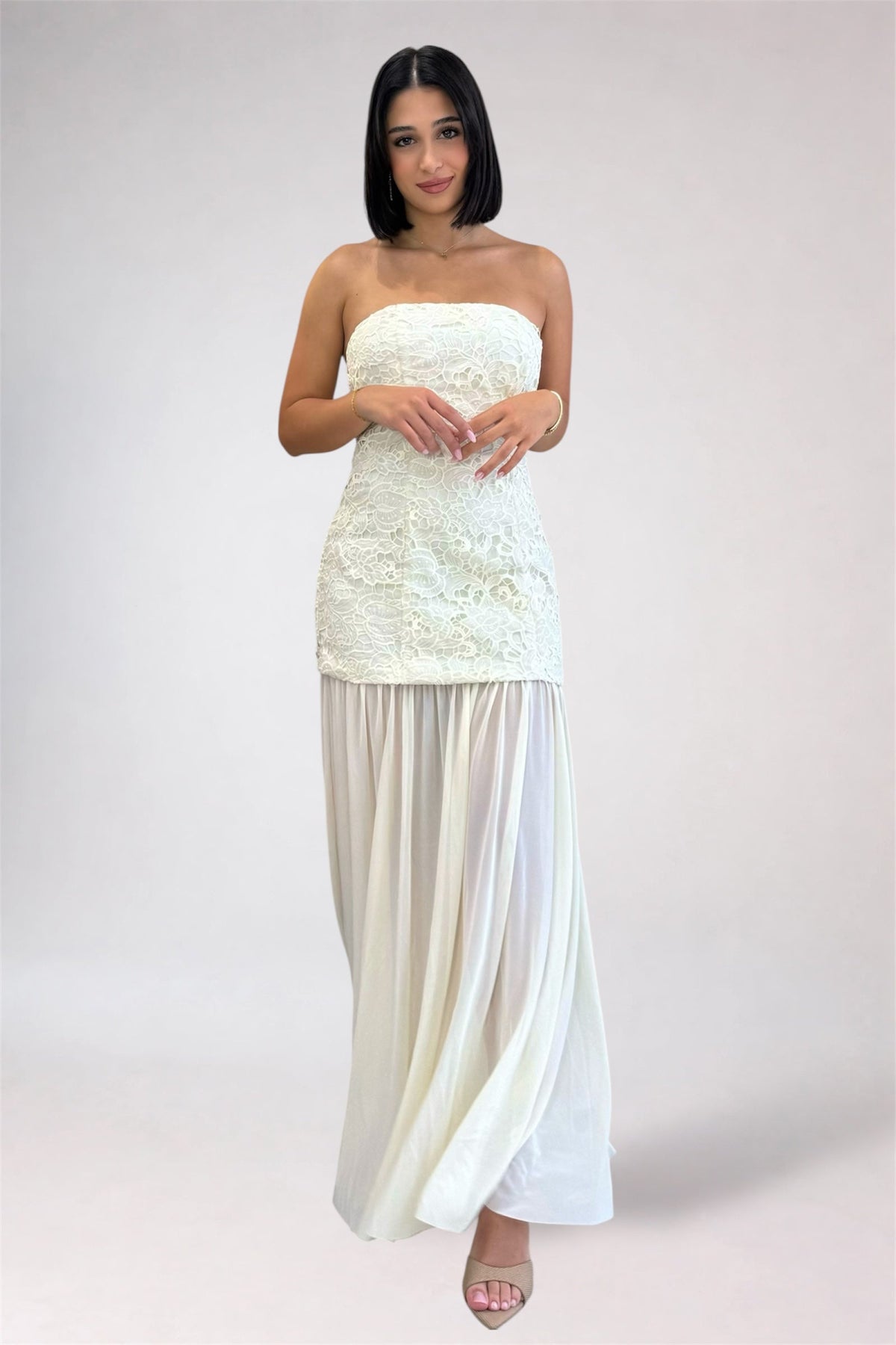 Woman wearing a strapless white dress with a plain background