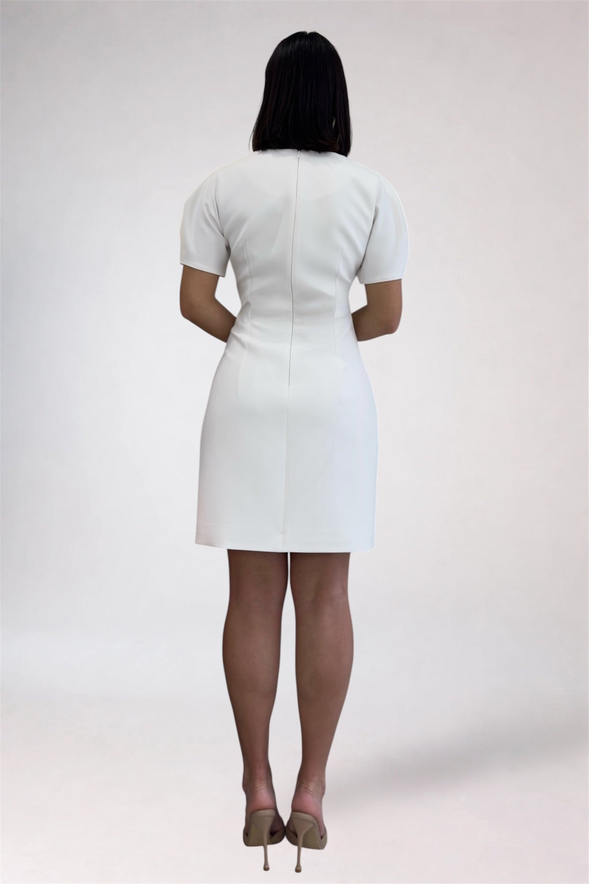 Person wearing a white dress on a plain background