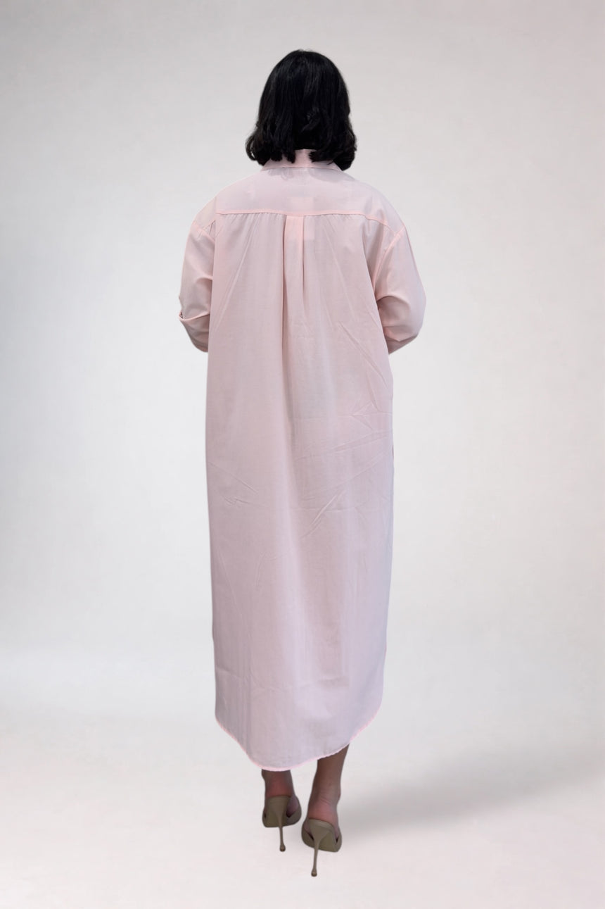 Person wearing a light pink dress with sheer sleeves on a white background