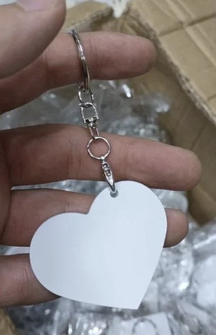 A blank white heart metal keychain tag with a silver metal split ring and clasp, held by a hand.
