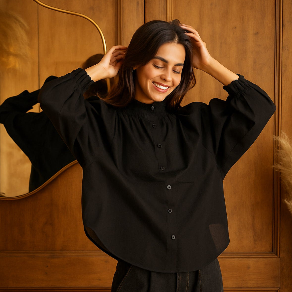 Woman in a black shirt standing against a wooden paneled wall.