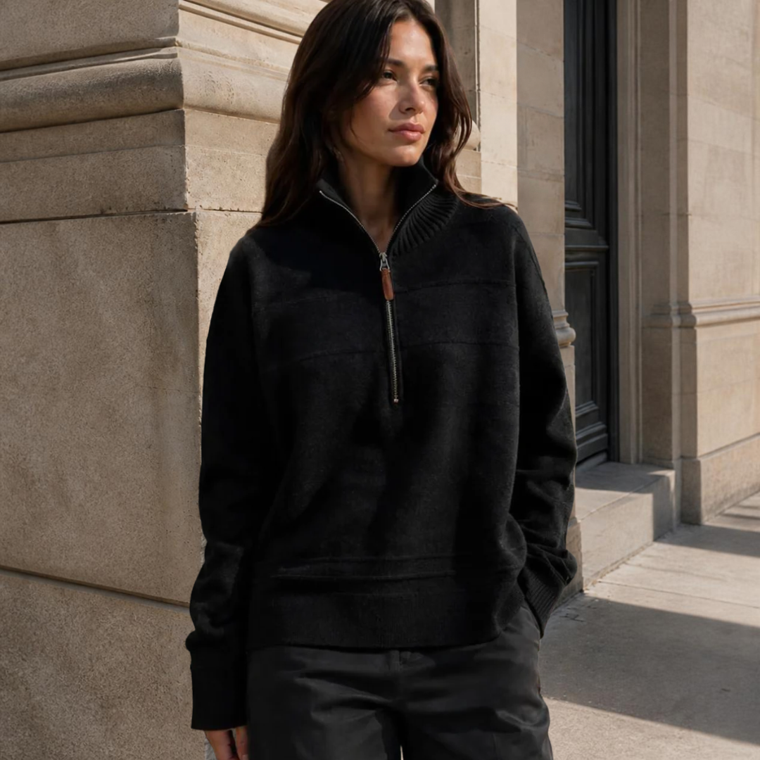 Model wearing KIDDING high-neck zip-up trucker sweater in black with ribbed collar, cuffs, and hem, paired with cream trousers