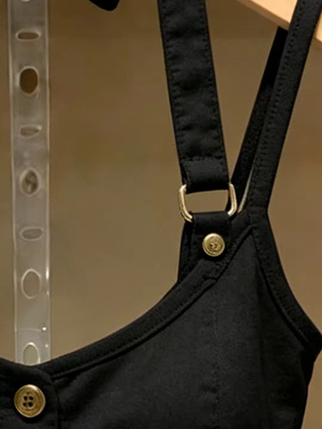 Closeup of black top gold hardware double straps and neckline