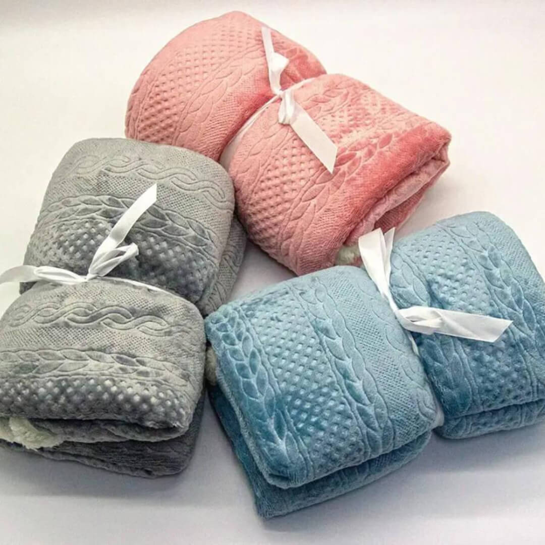 Three wearable folded blankets in pink, gray, and blue. 