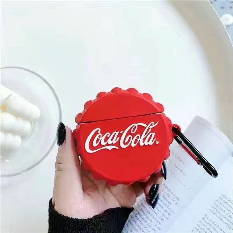 Red Coca-Cola air pod case held by a hand with a blurred background