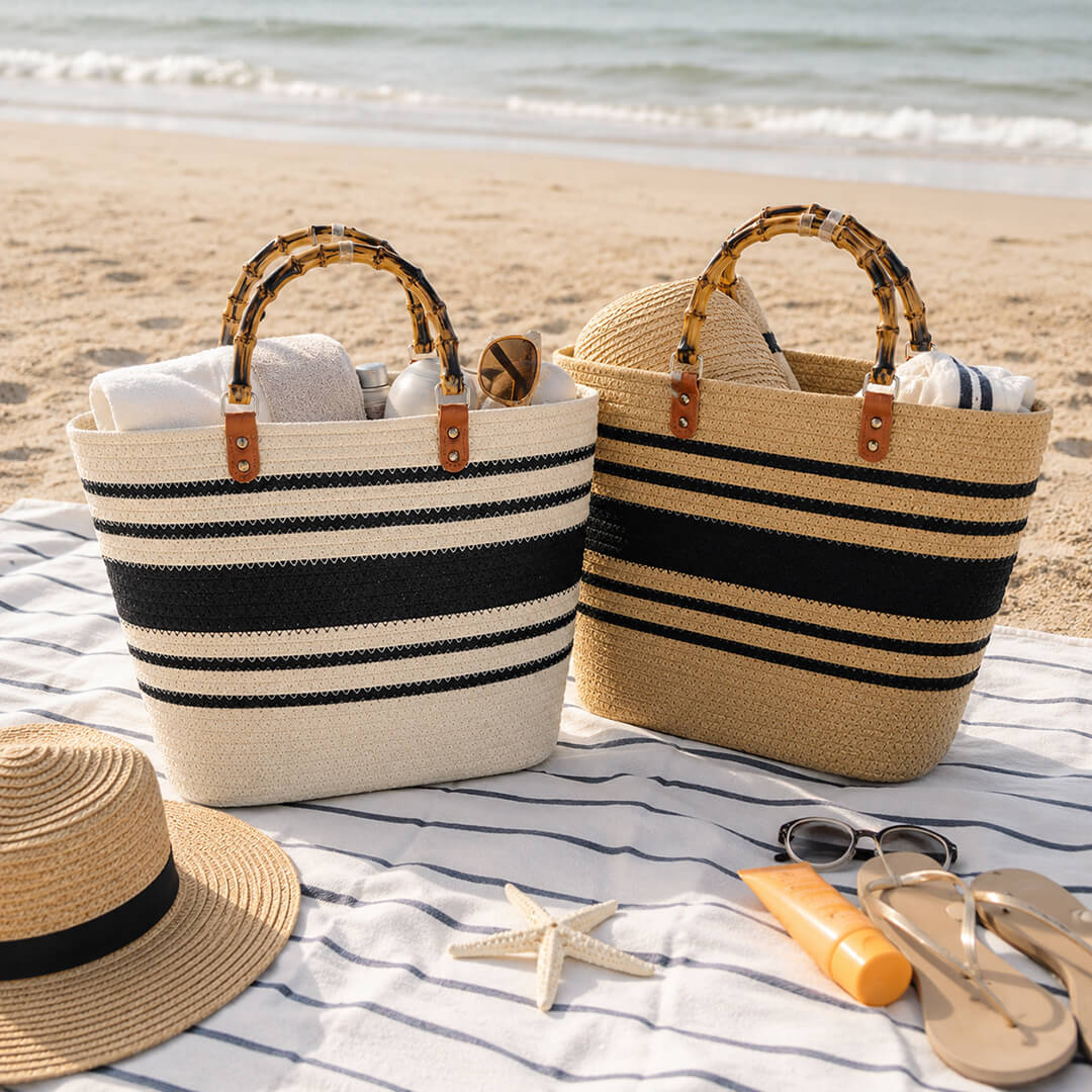 Two striped beach bags with a hat, sunglasses, and sunscreen at the beach.