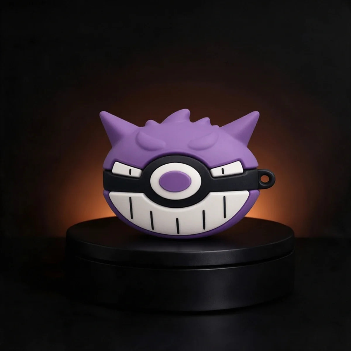 A purple Gengar-themed wireless earbud charging case cover displayed on a black circular pedestal against a dark background with warm lighting.