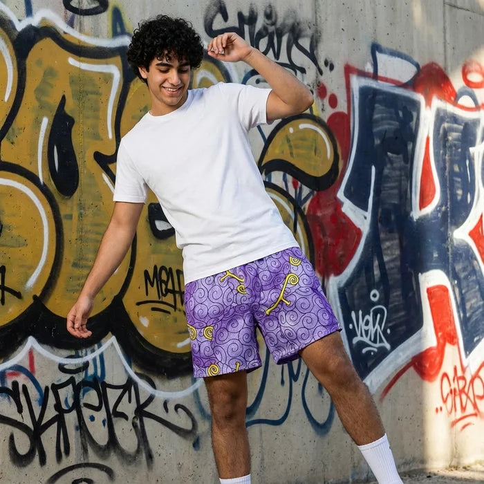 Person wearing a white t-shirt and purple shorts with yellow patterns in front of a graffiti-covered wall.