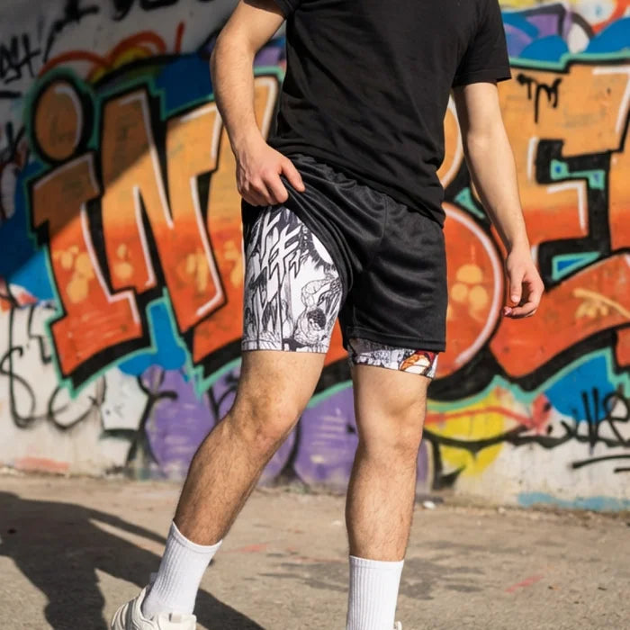 Person wearing black t-shirt and patterned shorts standing in front of a colorful graffiti wall.