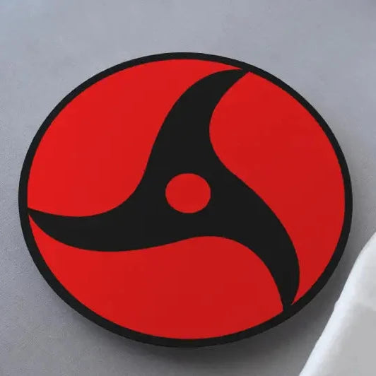 A round black, red, and white coaster with the Mangekyou Sharingan design from the anime Naruto.