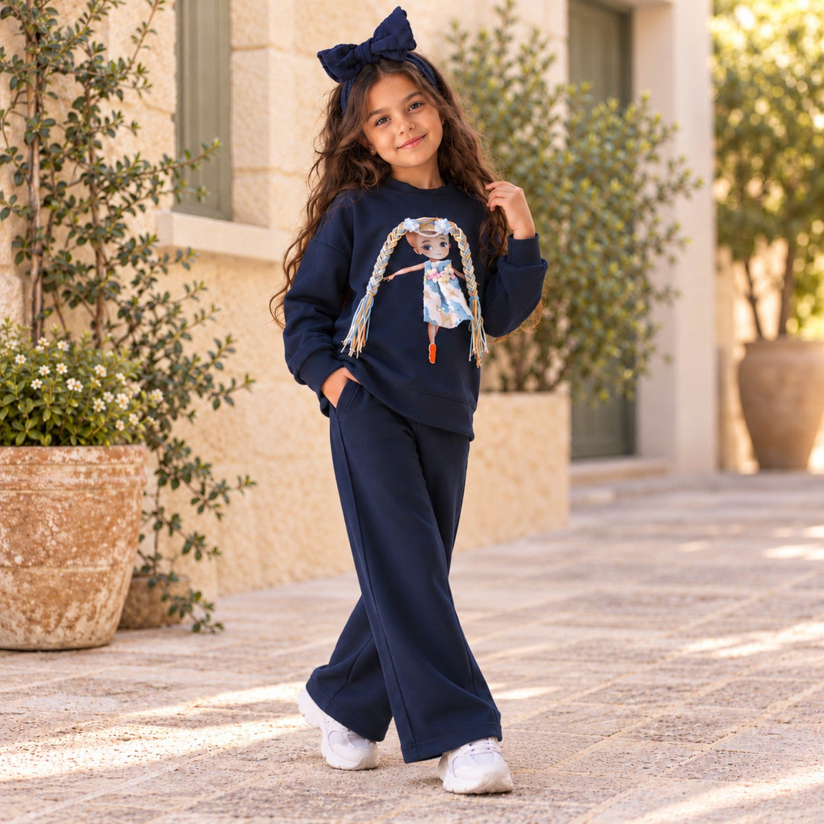 Girl wearing navy wide-leg trouser set with doll applique on sweatshirt