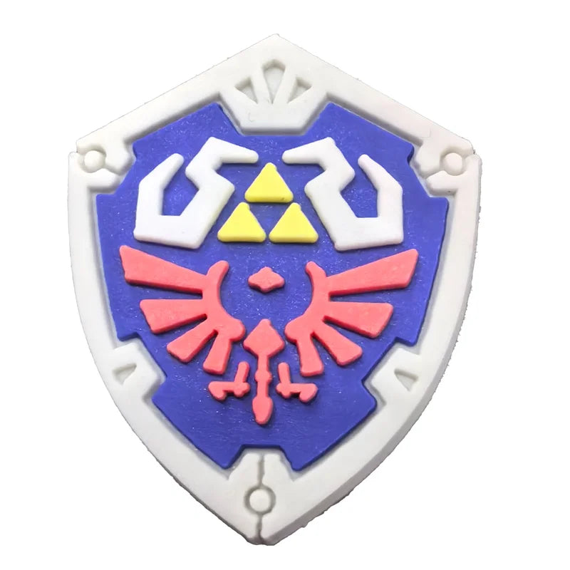 legend of zelda croc charms for crocs | jibbitz shield-shaped emblem with a blue background, white outline, and pink and yellow design on a white background