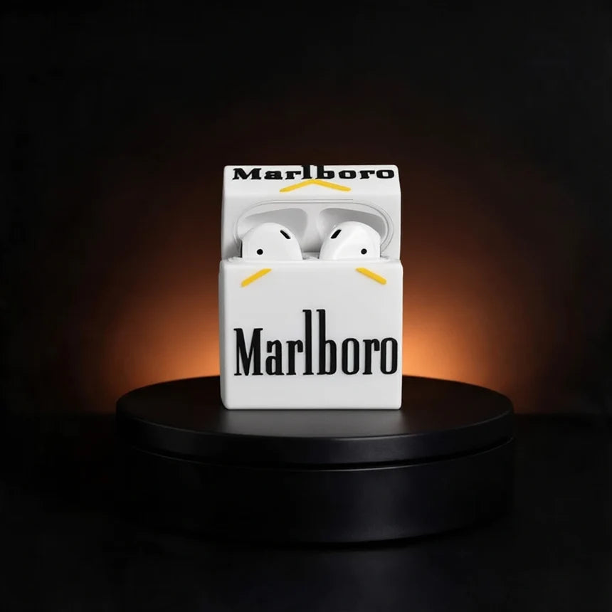 White wireless earbuds in a novelty cigarette-pack-style case printed with the Marlboro logo and yellow accent lines, displayed on a black pedestal against a dark background with warm light glow.