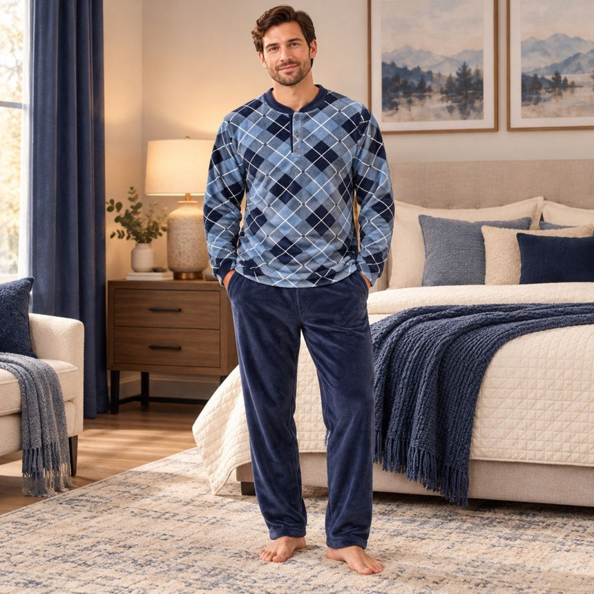 Man wearing a men's blue argyle warm pajama top and navy fleece pants in a cozy bedroom