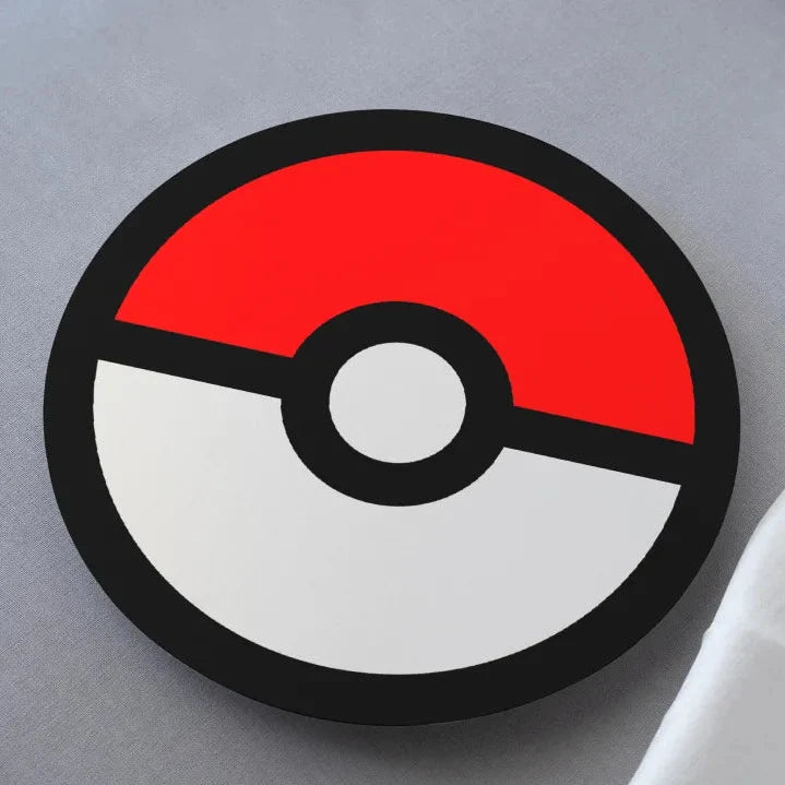 A coaster with a colorful pokemon pokéball design on it, placed on a white surface.