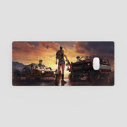 desk mat with a desert scene featuring vehicles and people against a sunset sky.