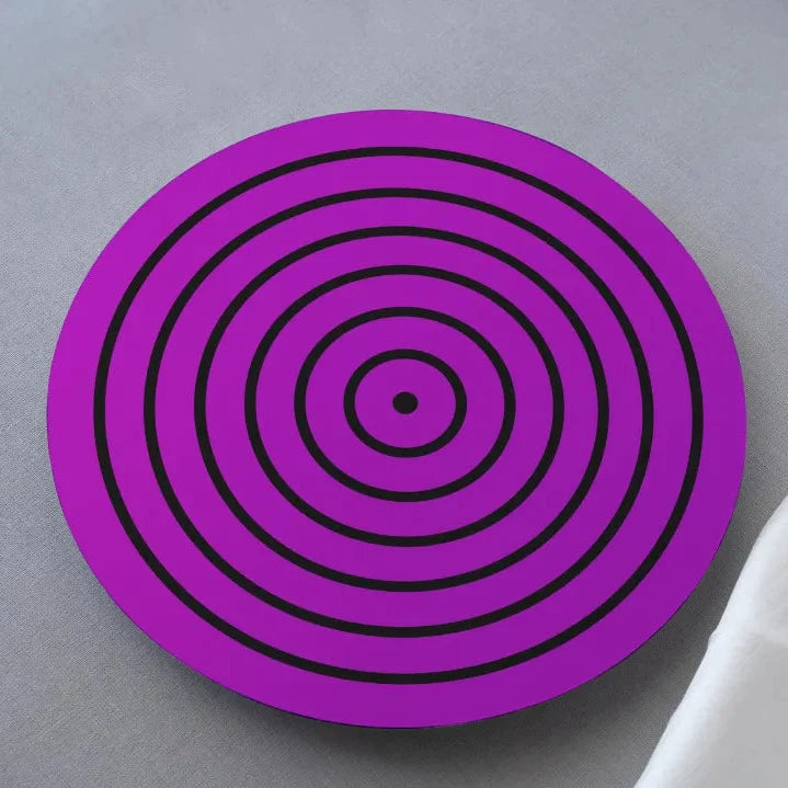 A purple coaster with a geometric Rinnegan eye design from the anime Naruto, placed on a surface with a white fabric in the background.
