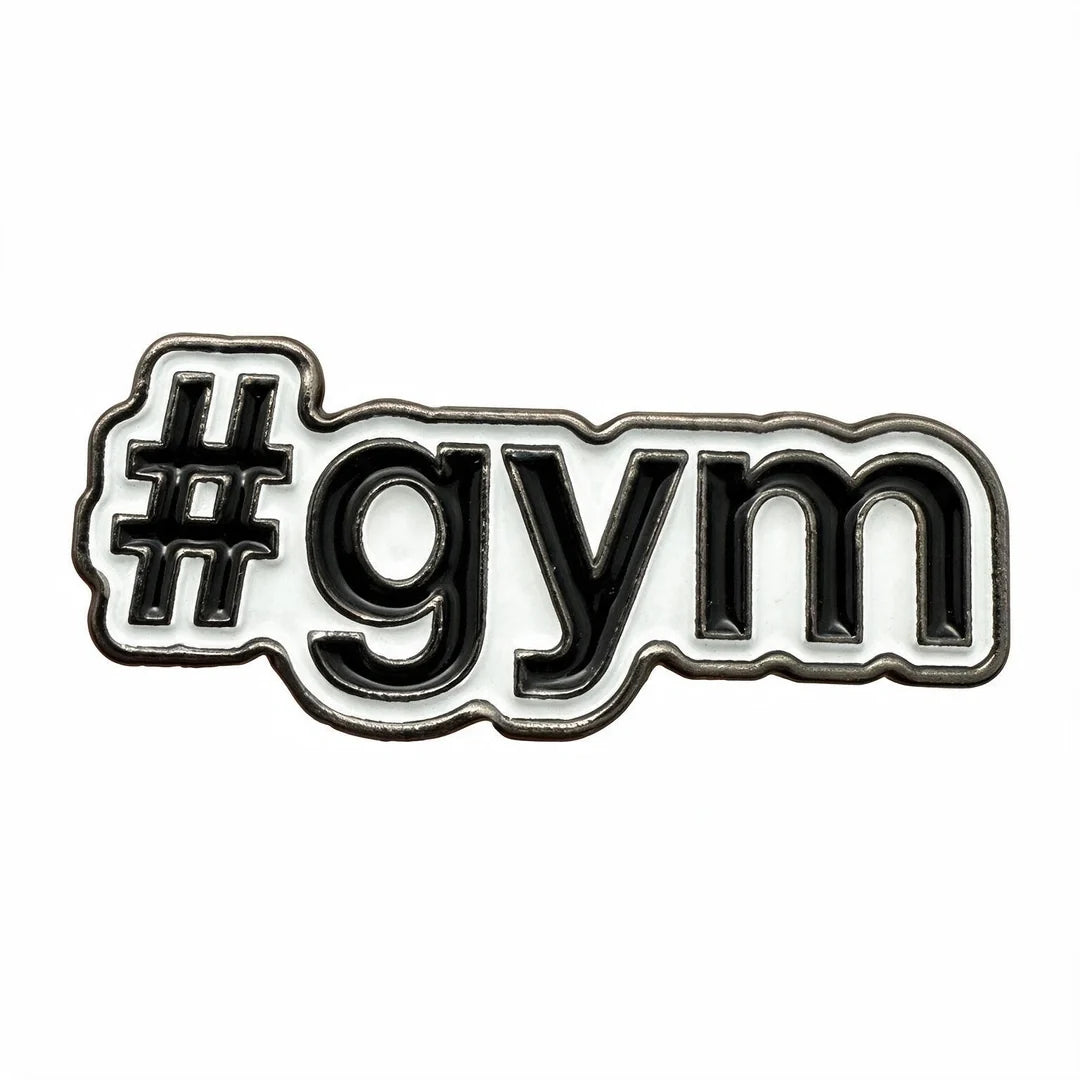 A close-up of a white enamel pin with black lettering that reads '#gym' on a plain white background.