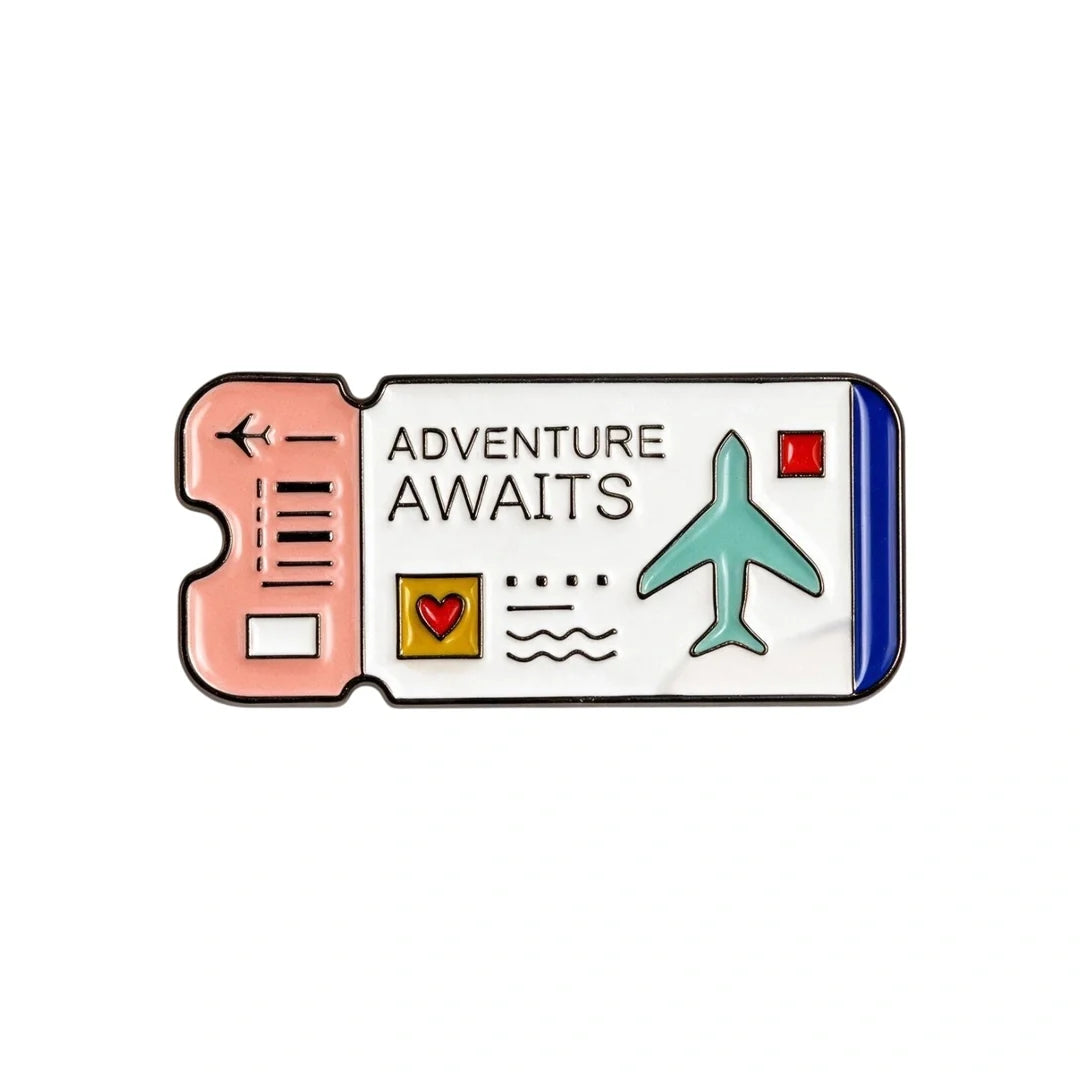 A travel ticket-shaped enamel phone sticker with the words 'ADVENTURE AWAITS' on a white panel, featuring a peach-pink left section, a blue right edge, a teal airplane, and small decorative icons.